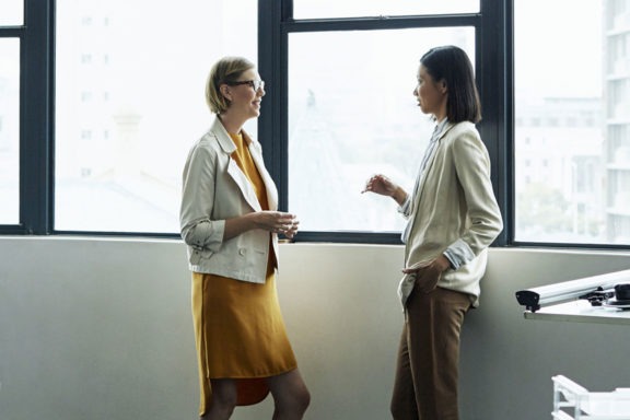 Two coworkers talking by window