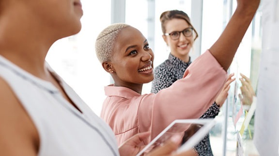 professional women collaborating on a white board