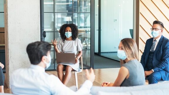 four professional in masks in a meeting