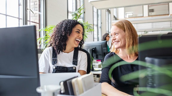 two women laughing at computers