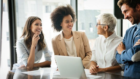 four professionals meeting around a laptop