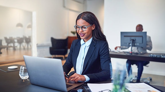 business woman sitting at a desk working at a laptop