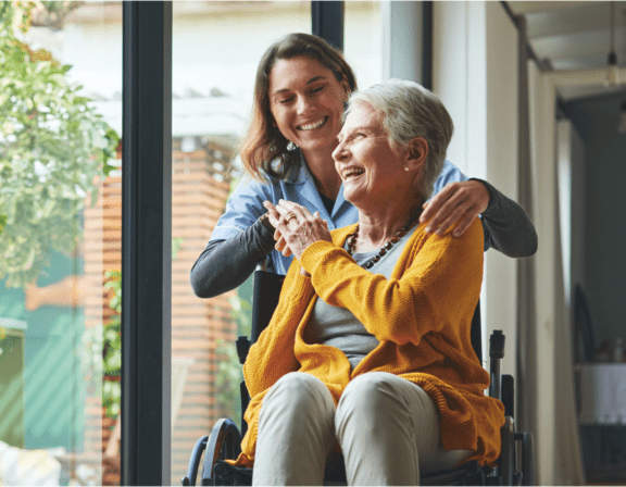 Older woman in wheelchair and female nurse laughing