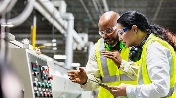 workers in a manufacturing plant inspecting machine