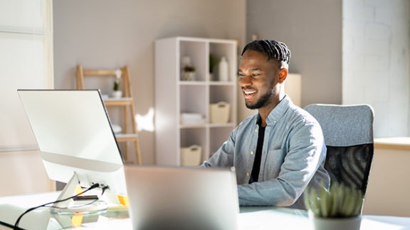 smiling worker sitting at desk in front of computer