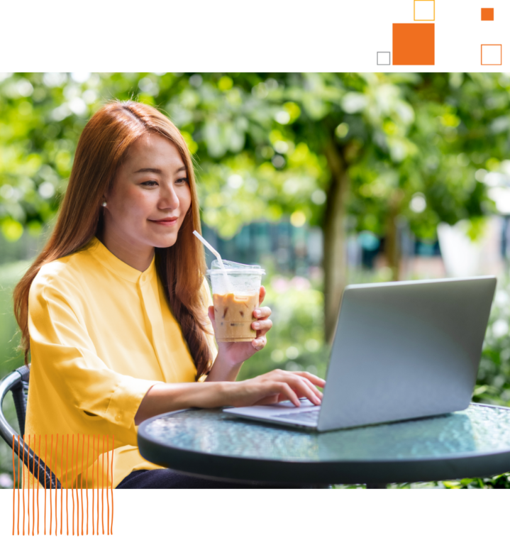 woman sitting outside with beverage cup using her laptop