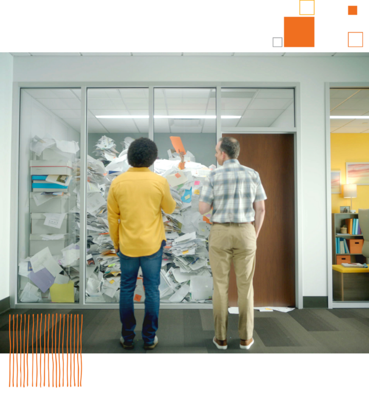 two people looking into office with giant pile of papers filling the room