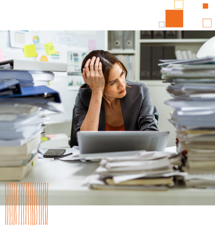 woman sitting at desk surrounded by piles of paper