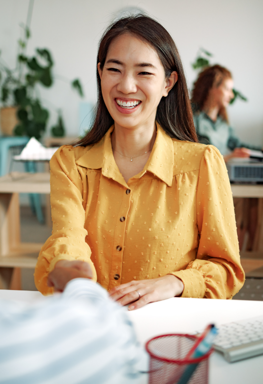 smiling woman shaking hand of someone across a table